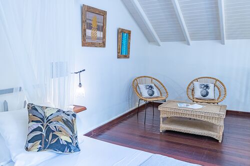 Vue d'un espace confortable avec deux chaises et une table basse ainsi que d'un lit dans un bungalow du Caraib'Bay Hôtel