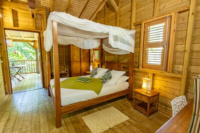 Vue du lit King Size à baldaquins dans la villa Ti Kaz Bwa du Caraïb'Bay Hôtel