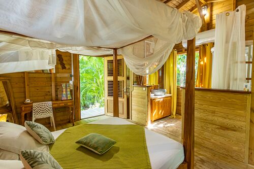 Vue de la chambre principale dans la villa Ti Kaz Bwa de l'hôtel Caraïb'Bay Hôtel avec un lit King Size et une salle de bains